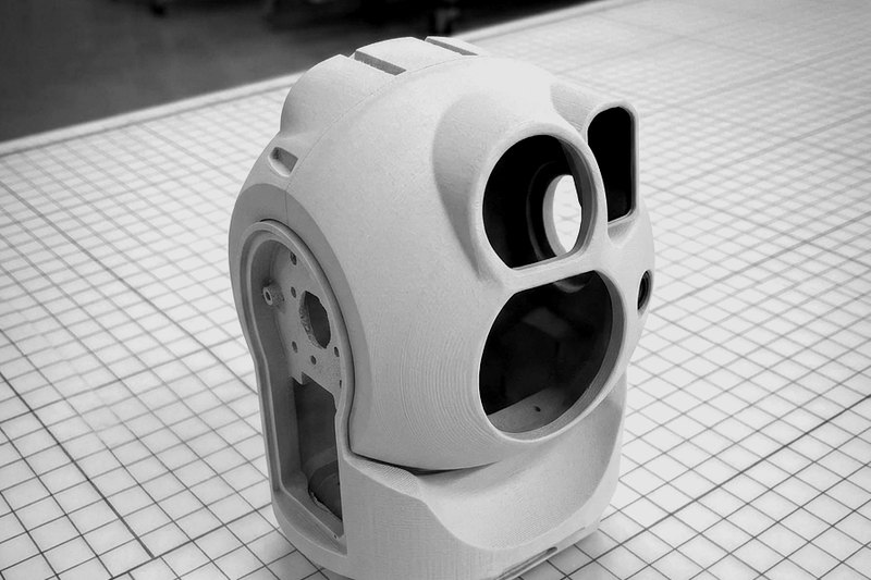 Additively manufactured prototype housing for a gimbal camera, with lens openings and a rotating head.